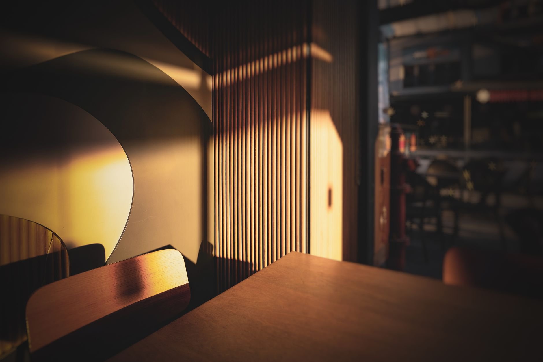 Warm sunlit corner of an empty cafe interior with wooden decor and ambient lighting.